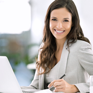 smiling businesswoman sitting beside laptop