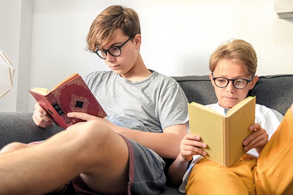 Brothers reading books with Child Trust Funds transferred to Foresters