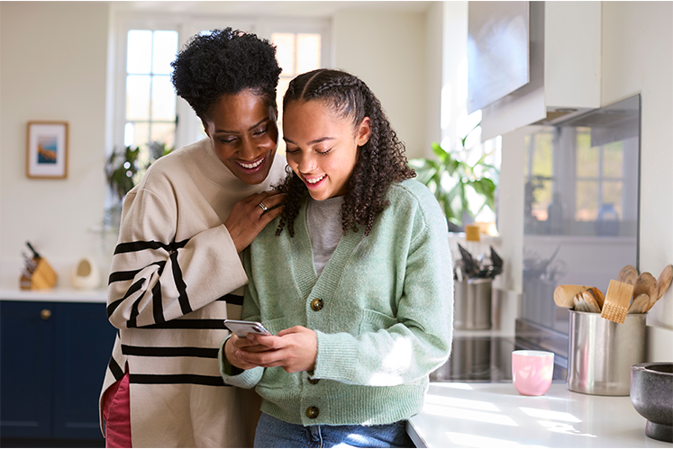 Mother and Daughter looking at mobile and smiling