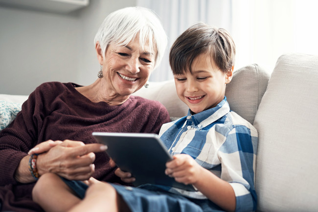Grandmother with grandson on tablet who is saving money into a Junior ISA on his behalf