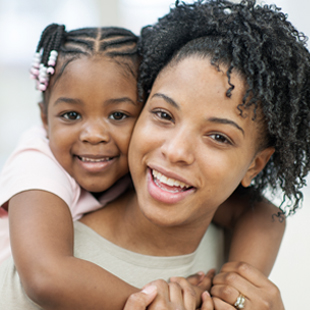 young girl with arms wrapped around smiling mother