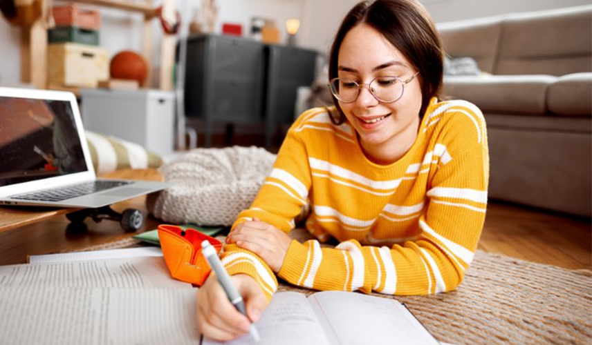 Une jeune femme qui lit un manuel scolaire en prenant des notes